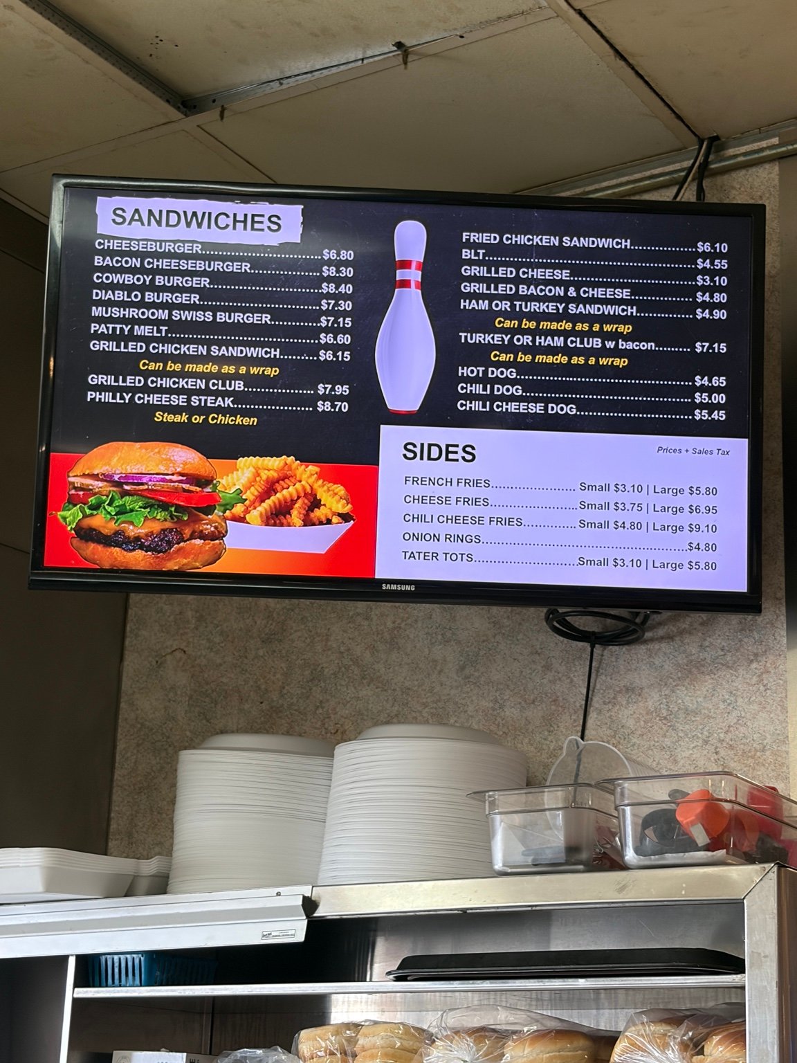 Ten Pin Lanes menu board showing sandwiches, burgers, hot dogs, and sides.